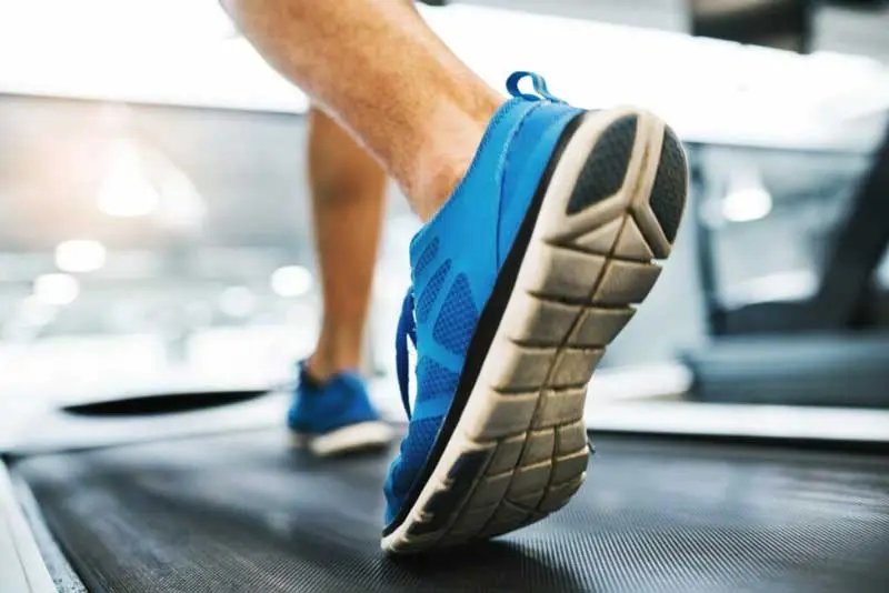 feet of young man in gym running on treadmill scaled 1